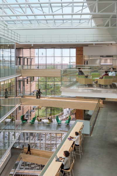 Light-filled atrium with exposed concrete and steel structure and wood finishes.