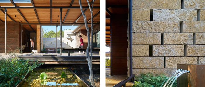 Wood and steel canopy over an outdoor wood deck surrounded by stone walls and water features. 