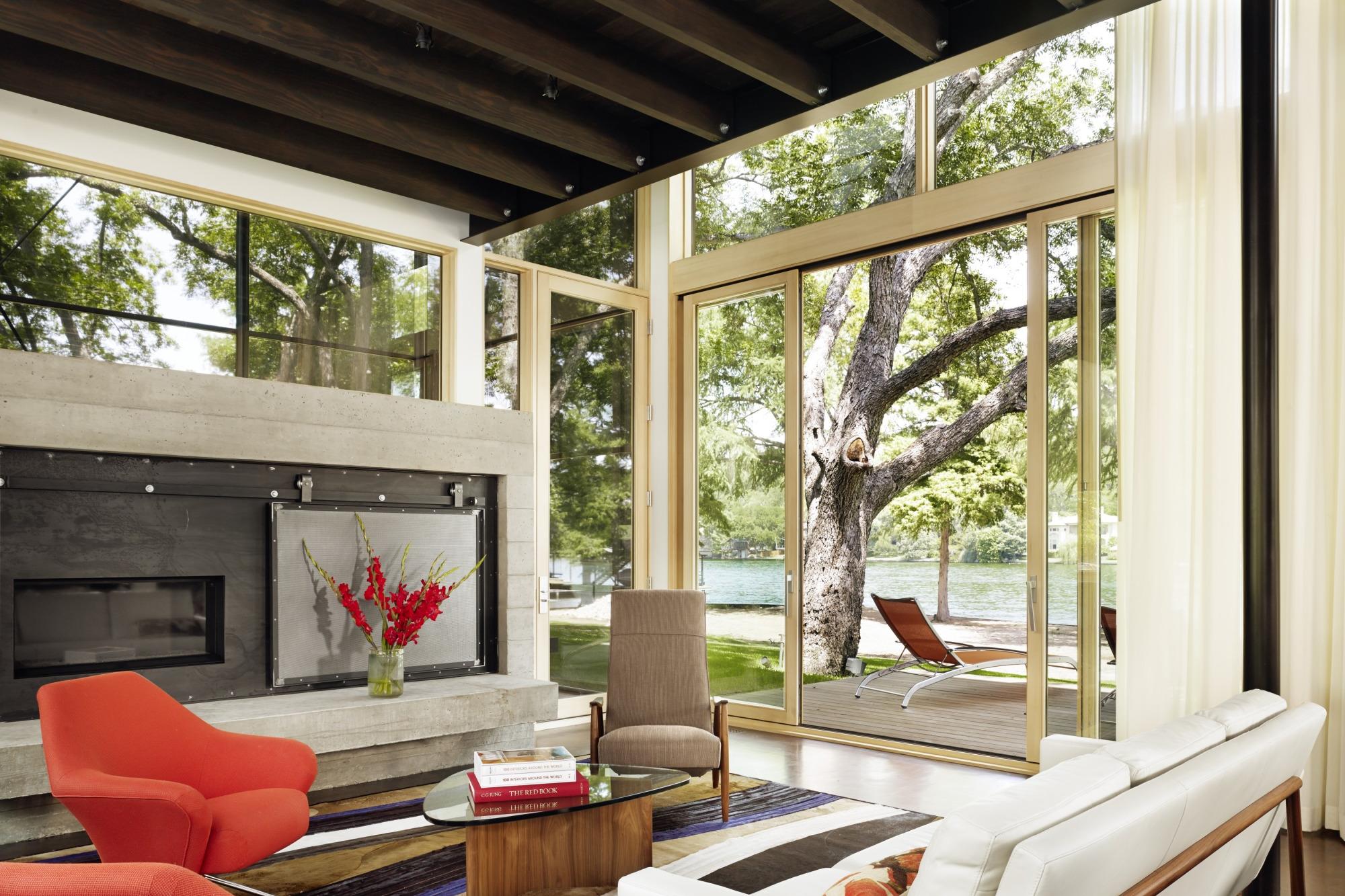 Hog Pen Creek Residence was envisioned by its owners as a place that evokes the playfulness of summer on the lake. Interior image looking across the living room seating area with views to outside porch and lake.