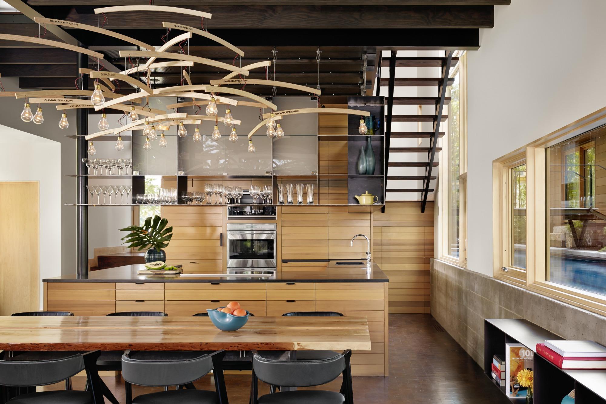 Situated at the confluence of Hog Pen Creek and Lake Austin, Hog Pen Creek Residence was envisioned by its owners as a place that evokes the playfulness of summer on the lake. Interior image looking across custom wood dining table and chandelier with view