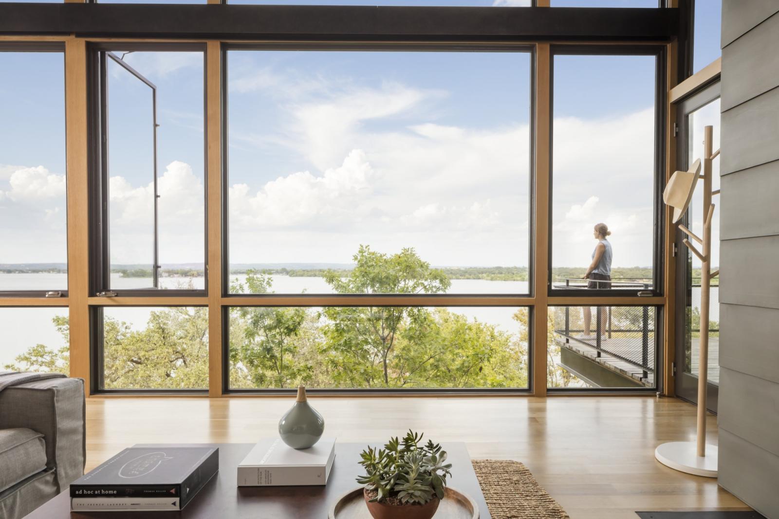 From the living room, the third floor north-facing glazed wall offers unobstructed views of the lake An award winning vertically structured lake house The long, narrow three-story residence dramatically culminates at the top floor, set just above the tree line and providing a nearly 180-degree view of the lake beyond