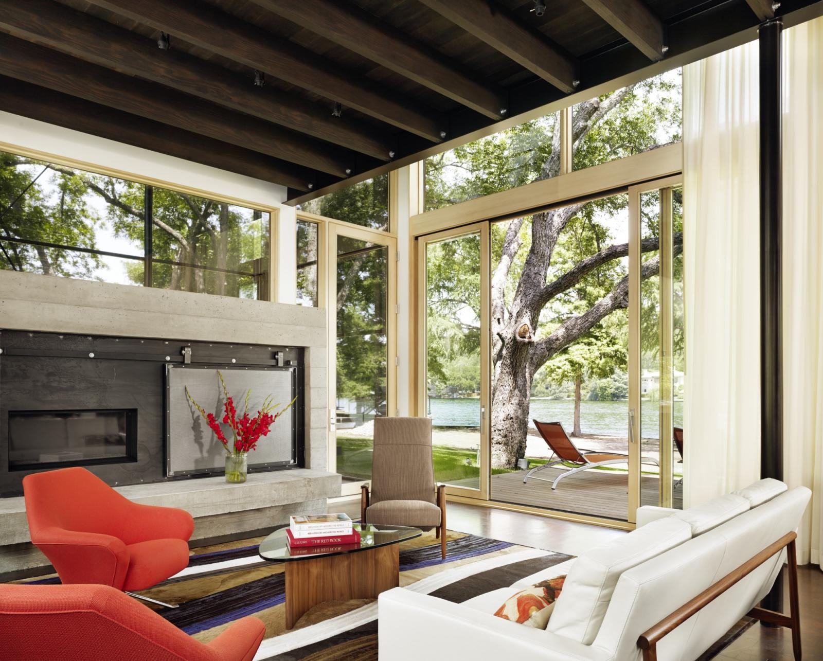 Hog Pen Creek Residence was envisioned by its owners as a place that evokes the playfulness of summer on the lake. Interior image looking across the living room seating area with views to outside porch and lake.