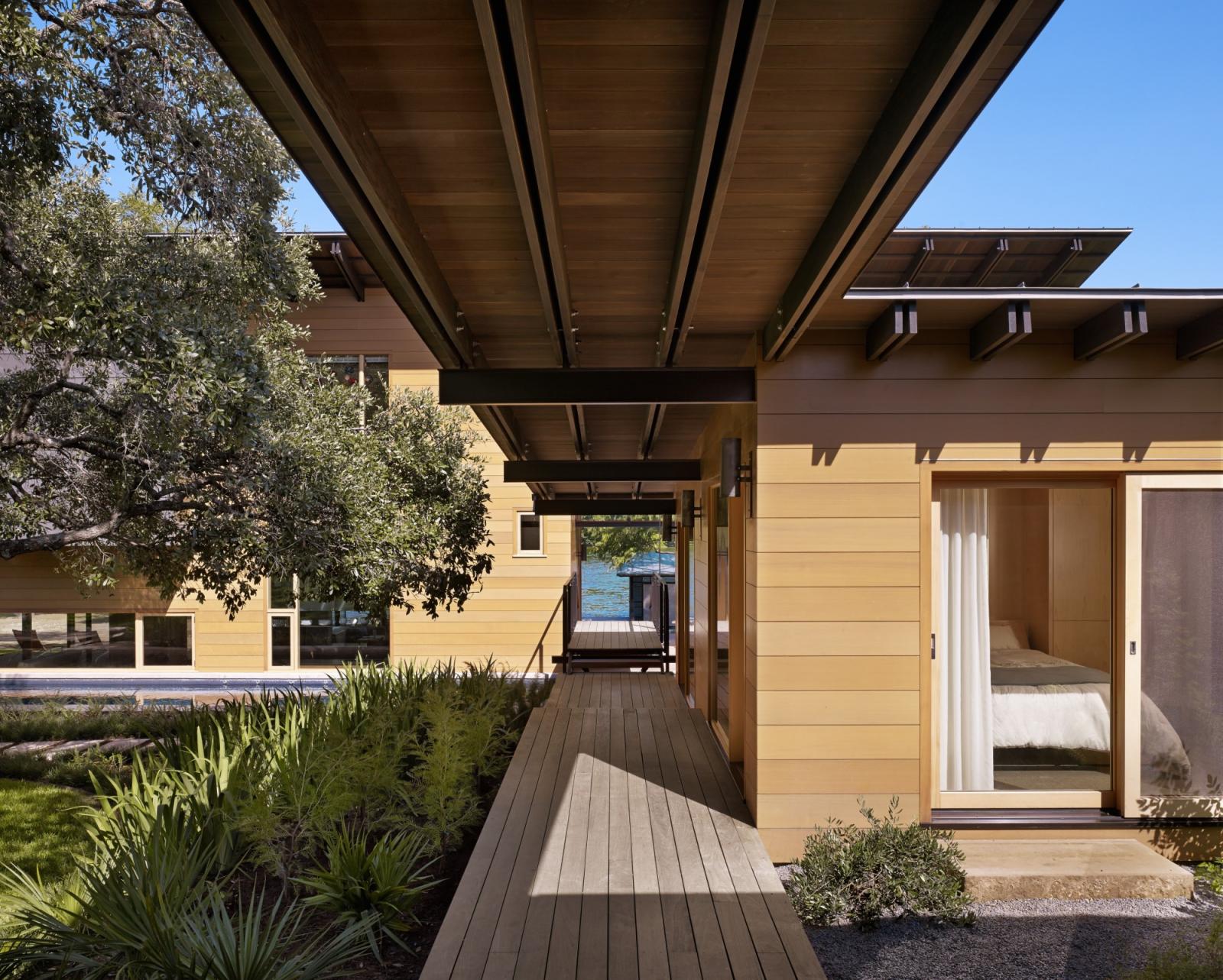 Hog Pen Creek Residence. A long exterior boardwalk connects a series of structures that stair step down the hillside, crossing a 75-foot lap pool and terminating at a screened pavilion by the water’s edge. 